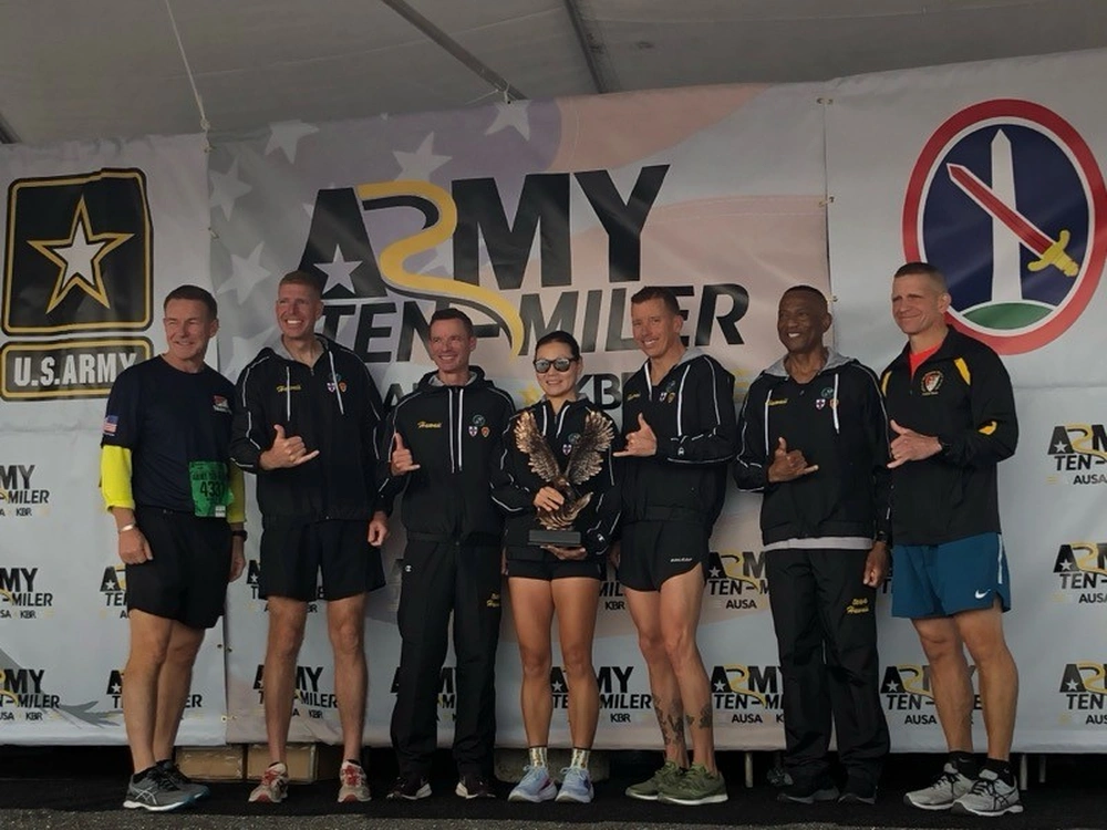 Army Ten Miler team on stage with award. U.S. Army logo visible.