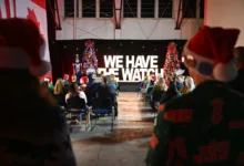 NORAD Tracks Santa event with "WE HAVE THE WATCH" banner and Christmas trees.