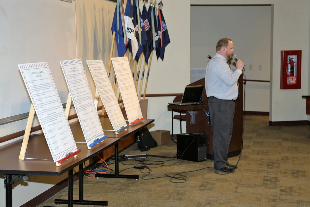 Speaker at podium with substance misuse awareness posters.