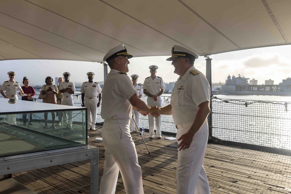 Navy officers shake hands during a promotion ceremony in Hawaii.