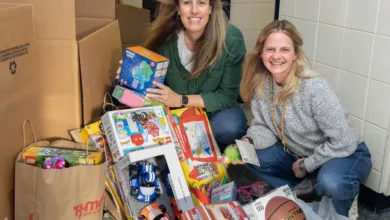 Two women with a large collection of toys, including LEGO sets and a basketball, for the Toys for Tots donation.