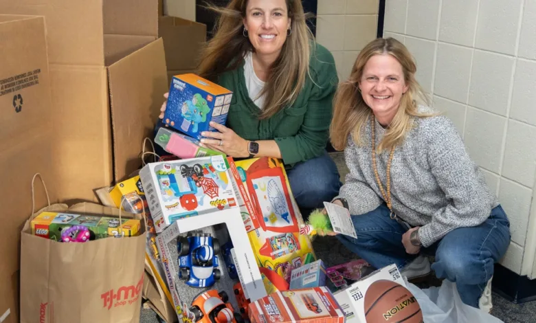 Two women with a large collection of toys, including LEGO sets and a basketball, for the Toys for Tots donation.