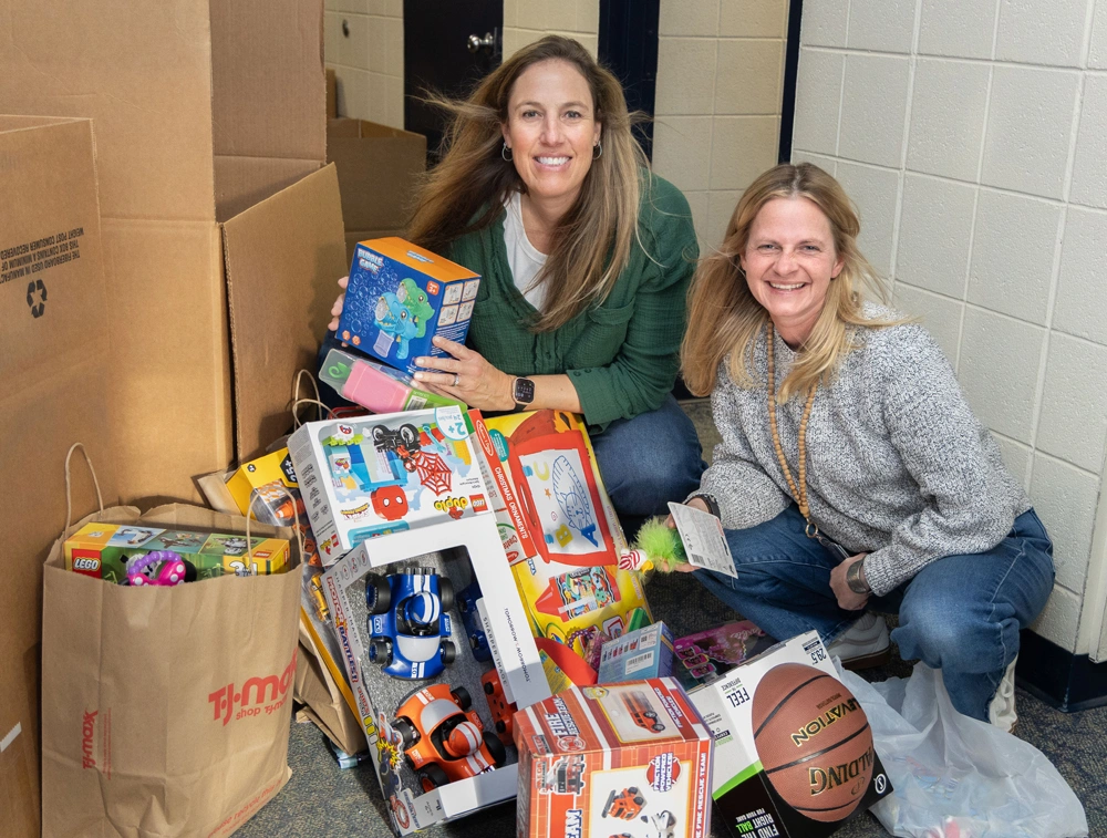 Two women with a large collection of toys, including LEGO sets and a basketball, for the Toys for Tots donation.