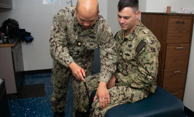Navy doctor examining a sailor's knee in a medical setting, potentially related to USS Carl Vinson medical operations.