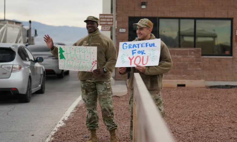 Airmen spread holiday cheer, holding signs "Happy Holidays" and "Grateful for You.