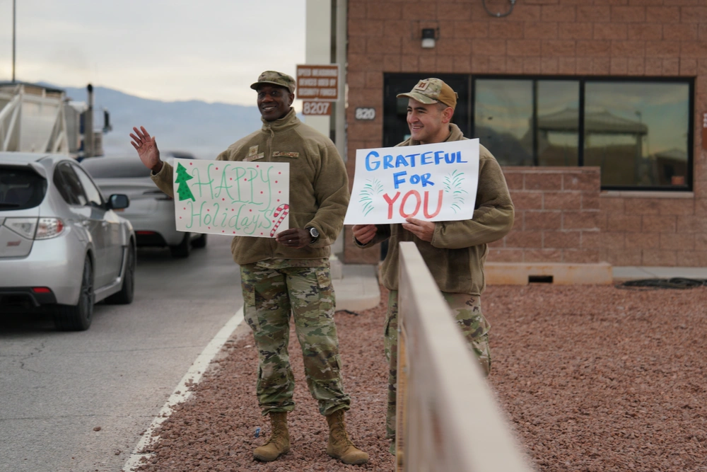 Airmen spread holiday cheer, holding signs "Happy Holidays" and "Grateful for You.