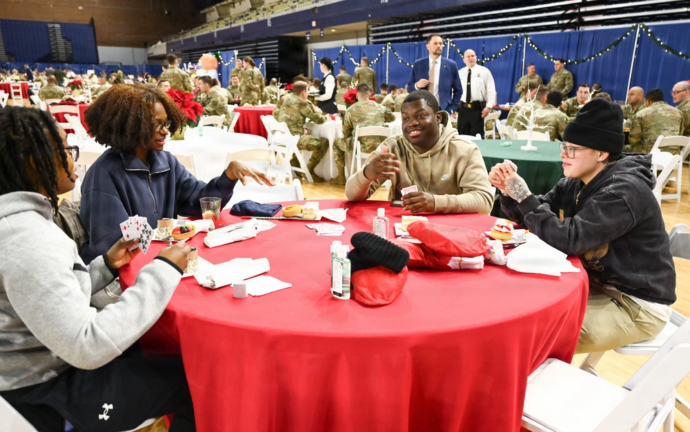 Guard members at D.C. Armory share a holiday celebration, playing cards at a table with a red tablecloth.