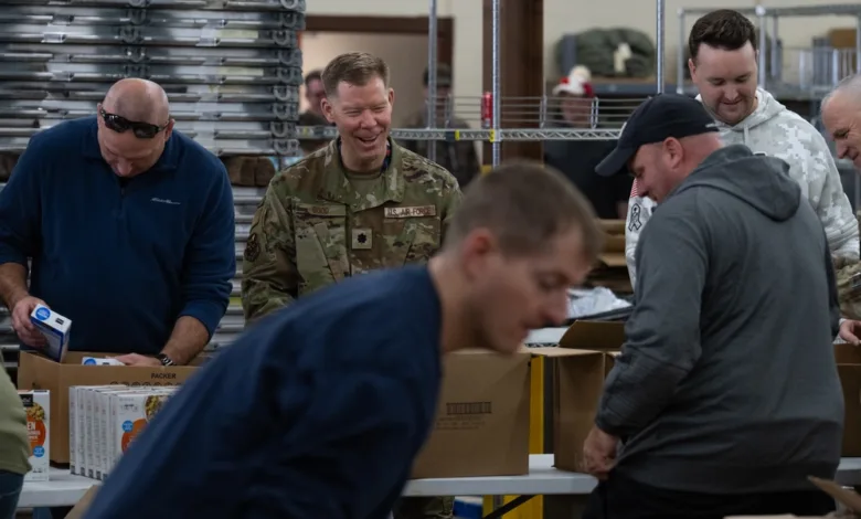 Volunteers, including an Air Force officer, assemble holiday baskets with food items for families.