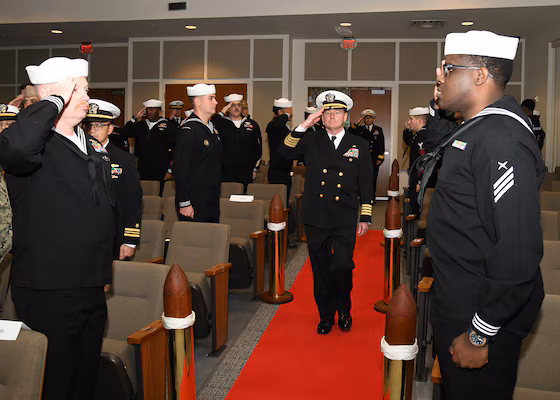 Navy personnel saluting during a ceremony, possibly related to information warfare.