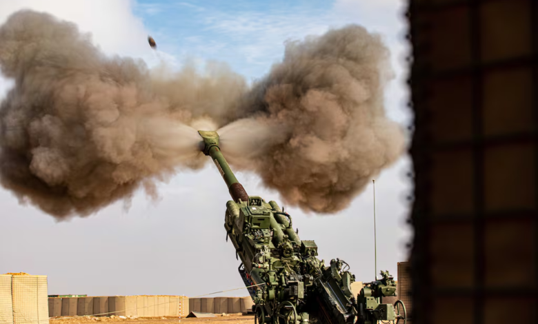 US Army howitzer firing a 155mm shell, creating a large smoke cloud.