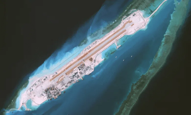 Aerial view of a militarized island outpost in the South China Sea with a long runway.