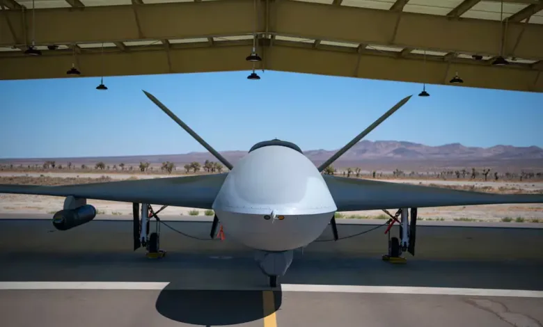 Front view of an Avenger drone under a hangar roof, ready for combat flight tests.