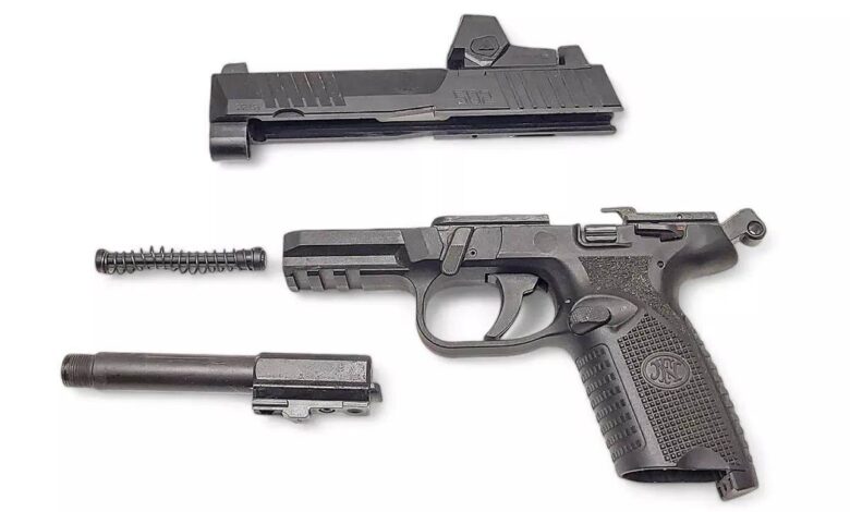 Disassembled FN 502 .22 LR handgun showing slide, frame, barrel, and recoil spring.