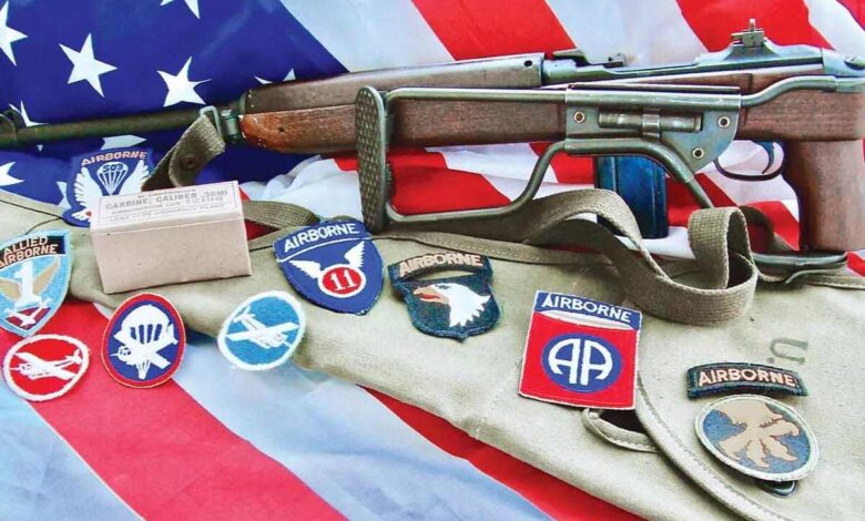M1A1 Carbine with Airborne patches and American flag. "Airborne" and "Carbine, Caliber .30MI" text visible.