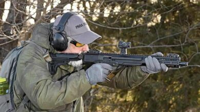 Man shooting Ruger LC Carbine in .45 ACP, wearing ear protection and grey gloves.
