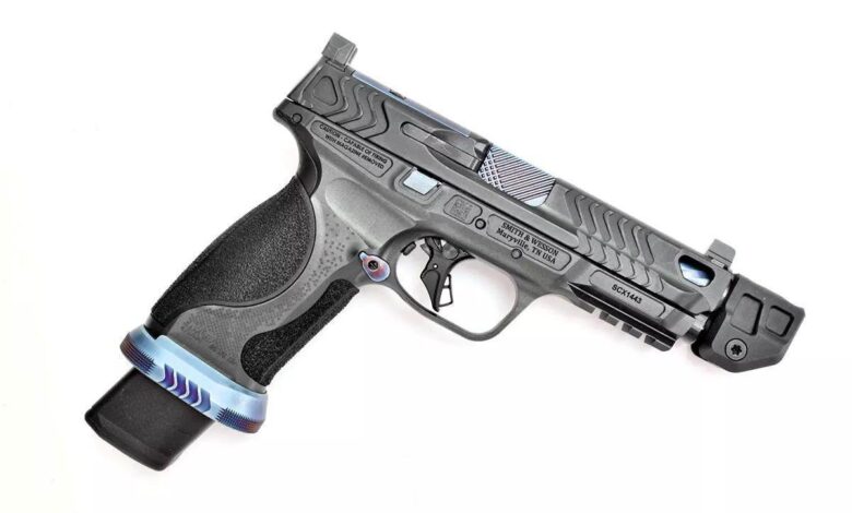 Custom Smith & Wesson M&P V series pistol with intricate slide design and extended magazine. Text: "CAUTION-CAPABLE OF FIRING WITH MAGAZINE REMOVED