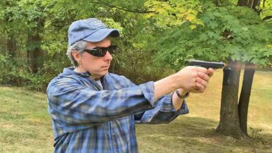 Man firing a Beretta Modello 1934 pistol outdoors.