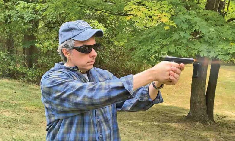 Man firing a Beretta Modello 1934 pistol outdoors.