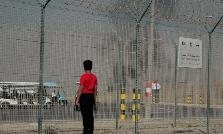 Boy near Airport Security Restricted Area fence with razor wire. Sign in Arabic and English.