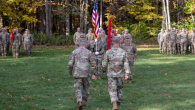 US Army soldiers in formation during an outdoor ceremony, flags visible.