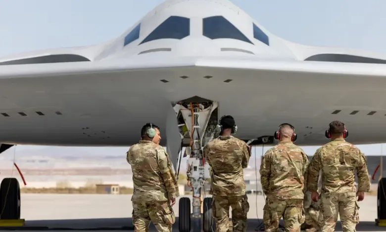 B-2 Spirit stealth bomber being inspected by U.S. Air Force personnel on a runway.