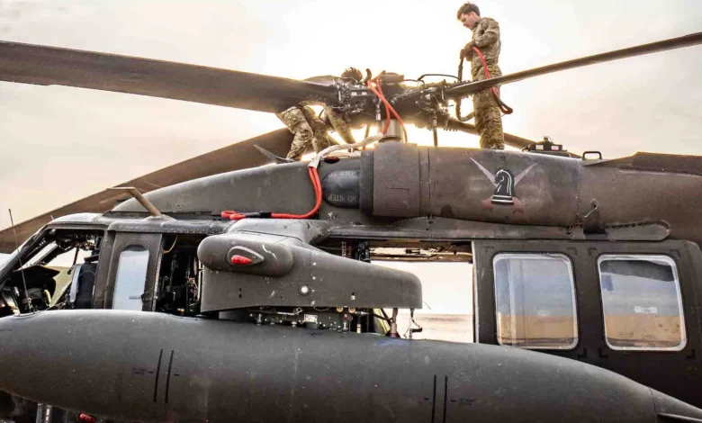 Army mechanics repair a Black Hawk helicopter. Pilot and mechanic switched units for a week.