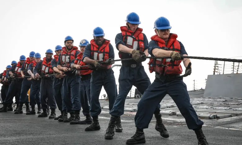 Navy sailors pulling a rope on a ship, extending service.