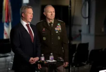 Man in suit and Army officer in uniform at a press conference.