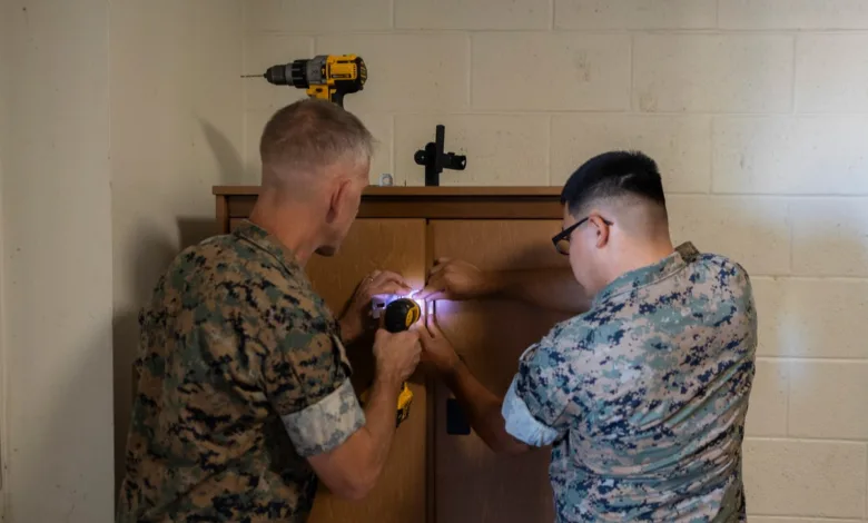 Barracks renovation: Two Marines repair a cabinet with a drill.