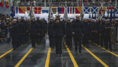 Navy recruits marching in formation during a ceremony.