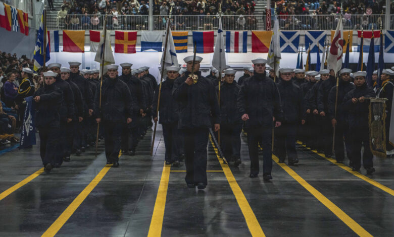 Navy recruits marching in formation during a ceremony.