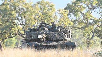 Camouflaged Australian Army tank in field, part of new armor acquisitions.