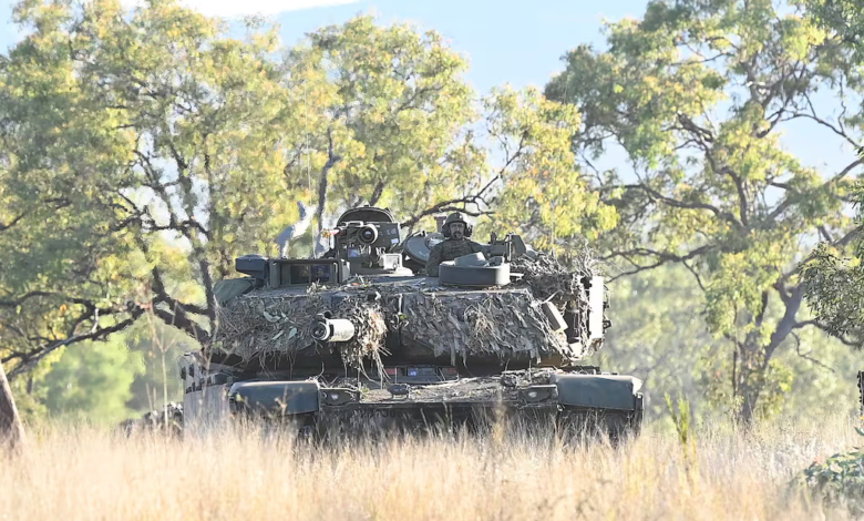 Camouflaged Australian Army tank in field, part of new armor acquisitions.
