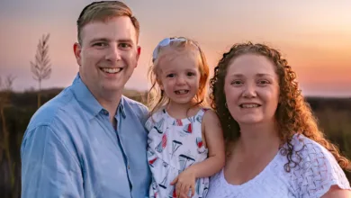 Happy family portrait at sunset. Mother, father, and young daughter smiling.