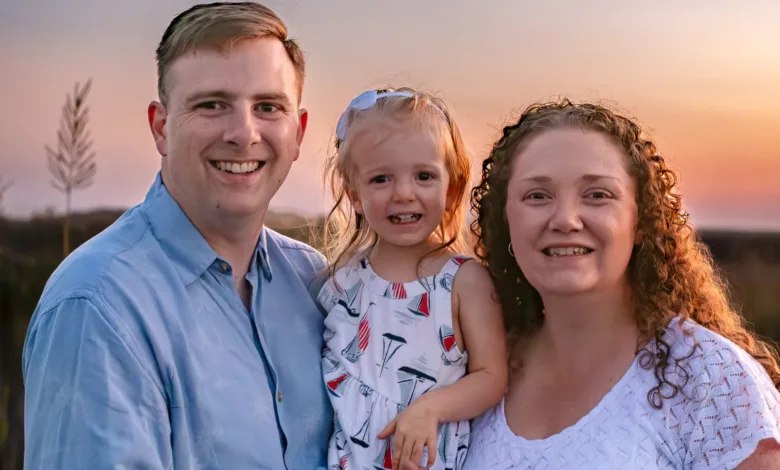 Happy family portrait at sunset. Mother, father, and young daughter smiling.