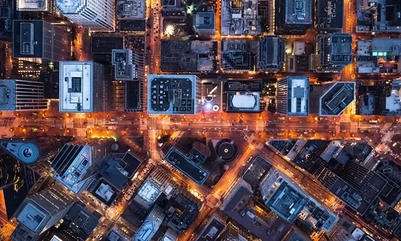 Aerial view of a city at night, showcasing illuminated buildings and streets.