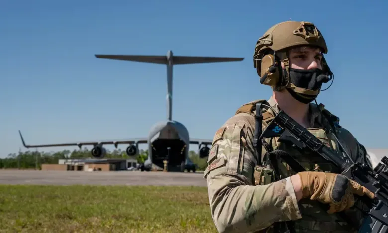 US Air Force security member stands guard in front of a C-17 Globemaster III aircraft.