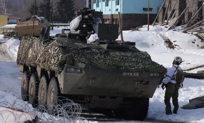 Slovenian Patria armored vehicle with camouflage netting in a snowy environment. SV 10-416 license plate visible.