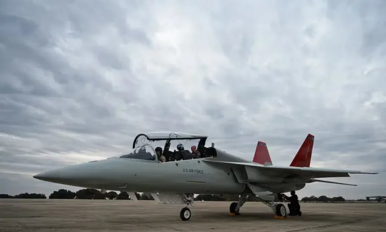 US Air Force T-7 trainer jet on the tarmac, instructor pilots visible in the cockpit.