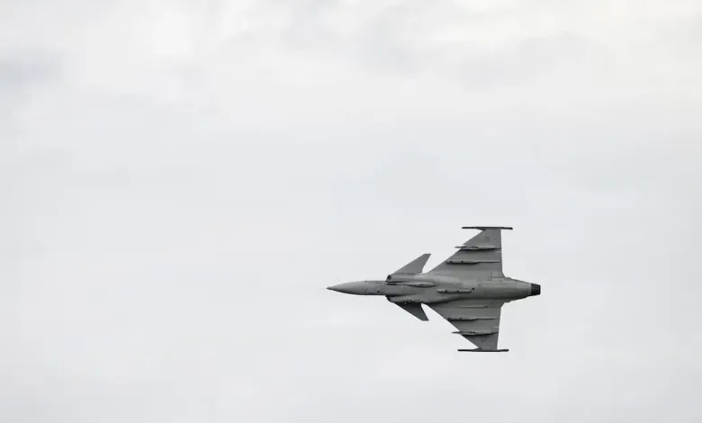 Swedish Gripen-E fighter jet in flight against a cloudy sky.
