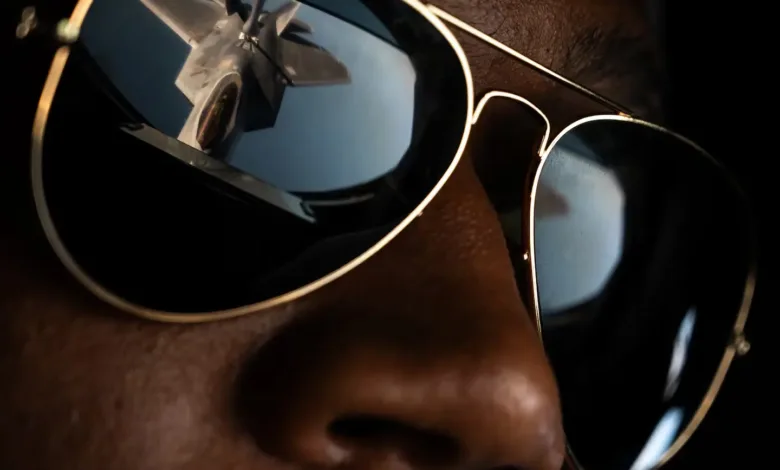 Close-up of aviator sunglasses reflecting a US Air Force fighter jet.