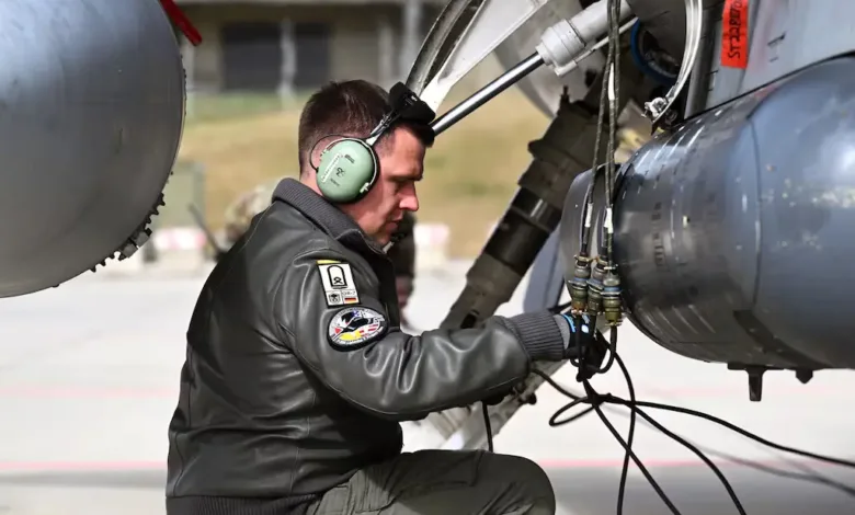 Technician inspecting a military jet, possibly related to US-Europe aviation cooperation.