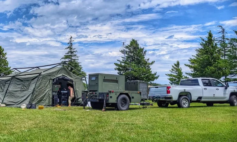 Air Force REFORPAC exercise: Military tent, generator trailer, and pickup truck on a grassy field under a cloudy sky.
