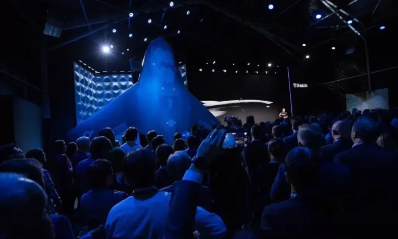 Shield AI unveils X-BAT autonomous fighter jet at a crowded event. Large model displayed.