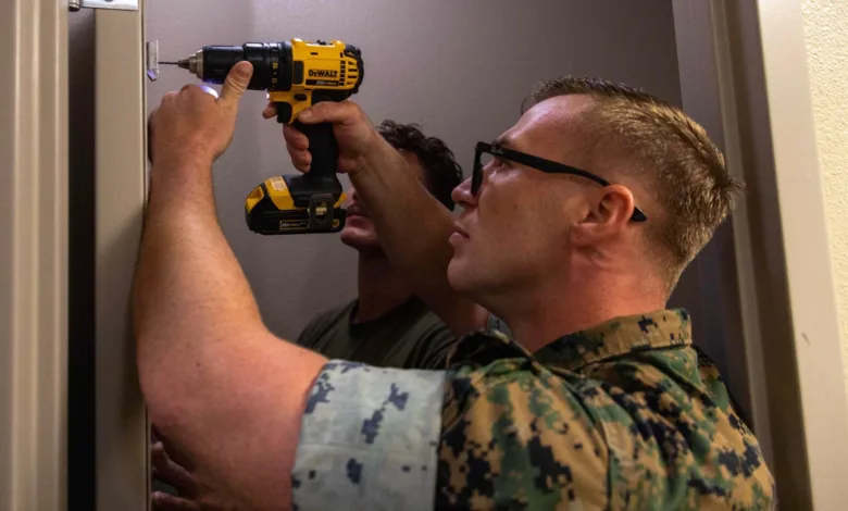 Man in military uniform using a drill on door frame.