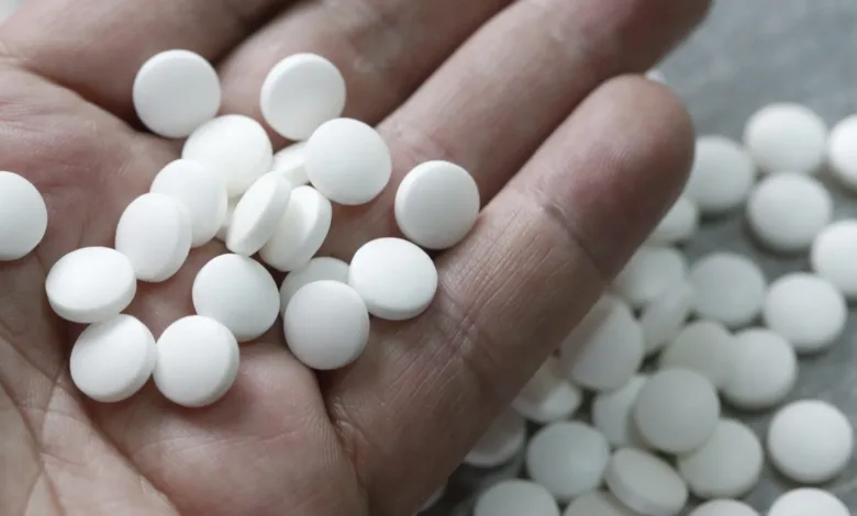 Hand holding white pills, possibly related to a PTSD nightmare drug recall for cancer risk.