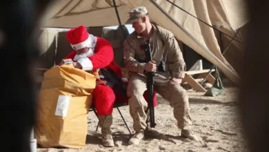 Santa with a Marine in a desert camp, sharing holiday cheer.