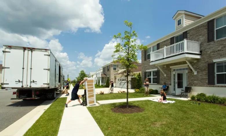 Moving truck at military family housing; movers unload furniture in a residential neighborhood.