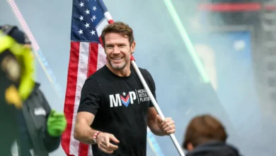 Nate Boyer carrying US flag. MVP: Merging Vets and Players.