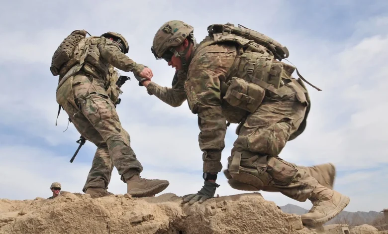 Soldiers helping each other climb terrain. Teamwork in action.